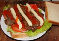 Lấy 1 lát bánh mì sandwich đặt bên dưới, phía trên là xà lách, cà chua, tiếp đến là thịt bò rồi cho tương ớt và sốt mayonaise cho vừa ăn lên.