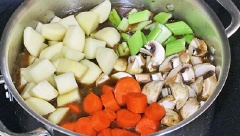 Sau 1 tiếng, nước trong nồi hơi cạn, đổ thêm 1 bát nước lạnh, cho khoai tây, cà rốt, hành tây, tỏi băm vào nồi. Nêm nếm gia vị vừa ăn, hầm trong 30 phút nữa.