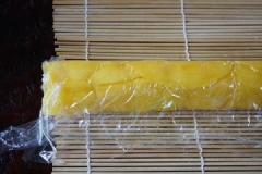 Trải 1 lớp màng bọc thực phẩm lên mành tre. Xếp xoài chín lên, cho xôi vào, dàn đều, cuộn tròn lại.