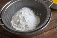 Rây bột mì, bột nở vào tô đường, trộn đều. Quậy tan trứng, vani và 15ml sữa tươi lại với nhau. Cho hỗn hợp trứng sữa vào tô bột, trộn đều. Hỗn hợp sau khi trộn sẽ đặc dẻo. Đun chảy bơ bằng lò vi sóng, chia thành 2 phần, cho từng phần vào tô bột trộn đều trước khi cho phần còn lại vào. Hỗn hợp cuối cùng sẽ hơi sền sệt, kéo phới lên bột sẽ nhiễu xuống thành dòng. Nếu bạn thích vị cam thì cho thêm phần vỏ bào từ 1 quả cam vào và trộn đều nhé, bánh sẽ rất là thơm đấy. Cho bột vào tủ lạnh nghỉ ít nhất 1 tiếng đồng hồ. Nếu để được qua đêm càng tốt.