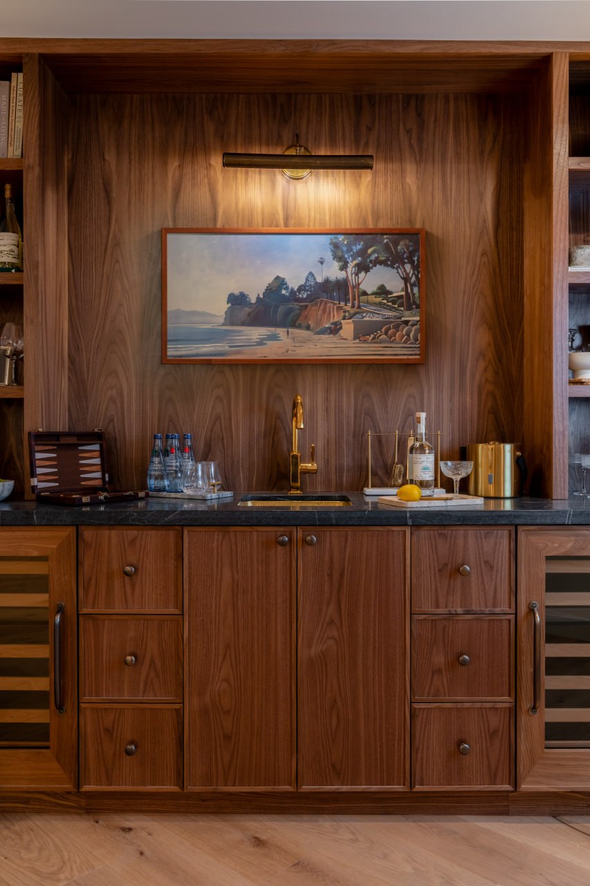 Custom walnut bar built-in with brass fixtures and Santa Barbara landscape painting — Kellow Construction