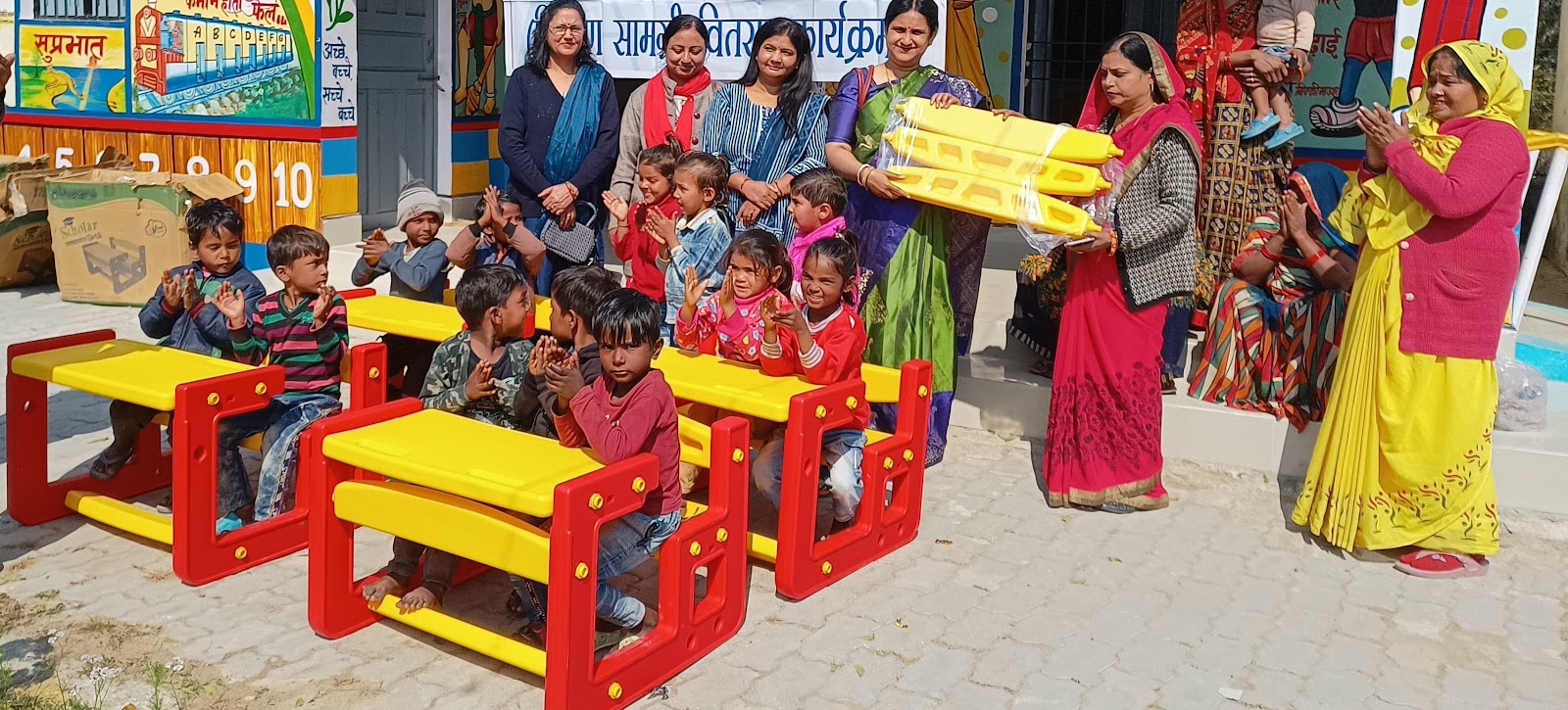 Children receiving classroom furniture through an education support activity