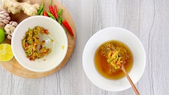 Cho gừng tỏi ớt đã giã nhuyễn vào tô nước mắm. Vắt thêm 30ml nước cốt chanh để nước mắm có vị chua thanh. Khuấy đều lần nữa là hoàn tất.