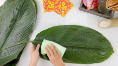 Cách làm bánh chưng gói lá dong: Phơi lá dong 1 nắng cho hơi héo và tạo độ dẻo để khi gấp lá gói bánh lá không bị rách hoặc nứt. Rửa lá dong với nước cho sạch rồi lau lại 2 mặt cho khô. Gấp lá dong lại làm 4, đo và cắt lấy 20 lá dong theo kích thước khuôn gói. Dùng dao tước bỏ gân lá, nhất là những gân lá quá lớn sẽ dễ châm thủng lá khi gói bánh chưng. Dậy lạt buộc bánh cũng nên ngâm nước vài tiếng đồng hồ để dây mềm dễ buộc hơn.