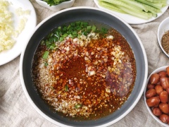 Làm hỗn hợp sốt trộn mì cay: cho vào chảo 1 muỗng canh ớt khô xay, 1 muỗng canh tỏi băm nhỏ, 1 muỗng canh hành lá, 1 muỗng canh mè trắng, 1/2 muỗng cà phê tiêu, 100-150ml dầu ô liu đun sôi, khuấy đều.