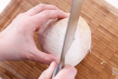 Dùng dao chặt phần đầu trên cùi dừa. Đổ nước dừa ra cốc và đặt vỏ trái dừa lên 1 cái chén.