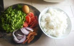 Cơm cho vào tô, trộn với ít nước, đảo đều để cơm không bị vón cục vào nhau. Xà lách rửa sạch, cắt nhỏ. Hành tím cắt mỏng. Cà chua 1 trái cắt múi cau nhỏ.