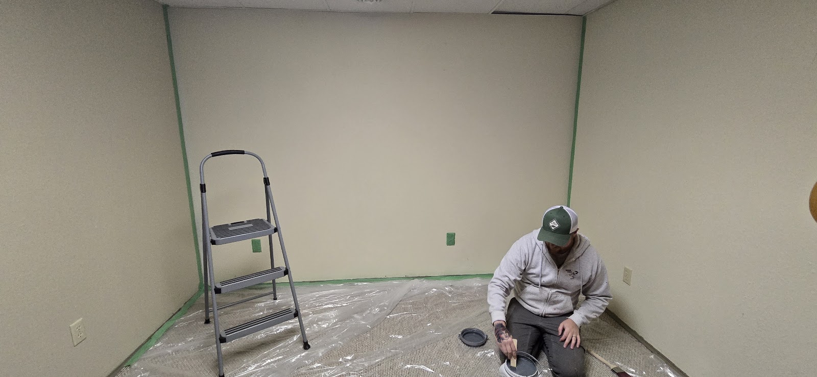Walls taped, ladder up — the painting begins.