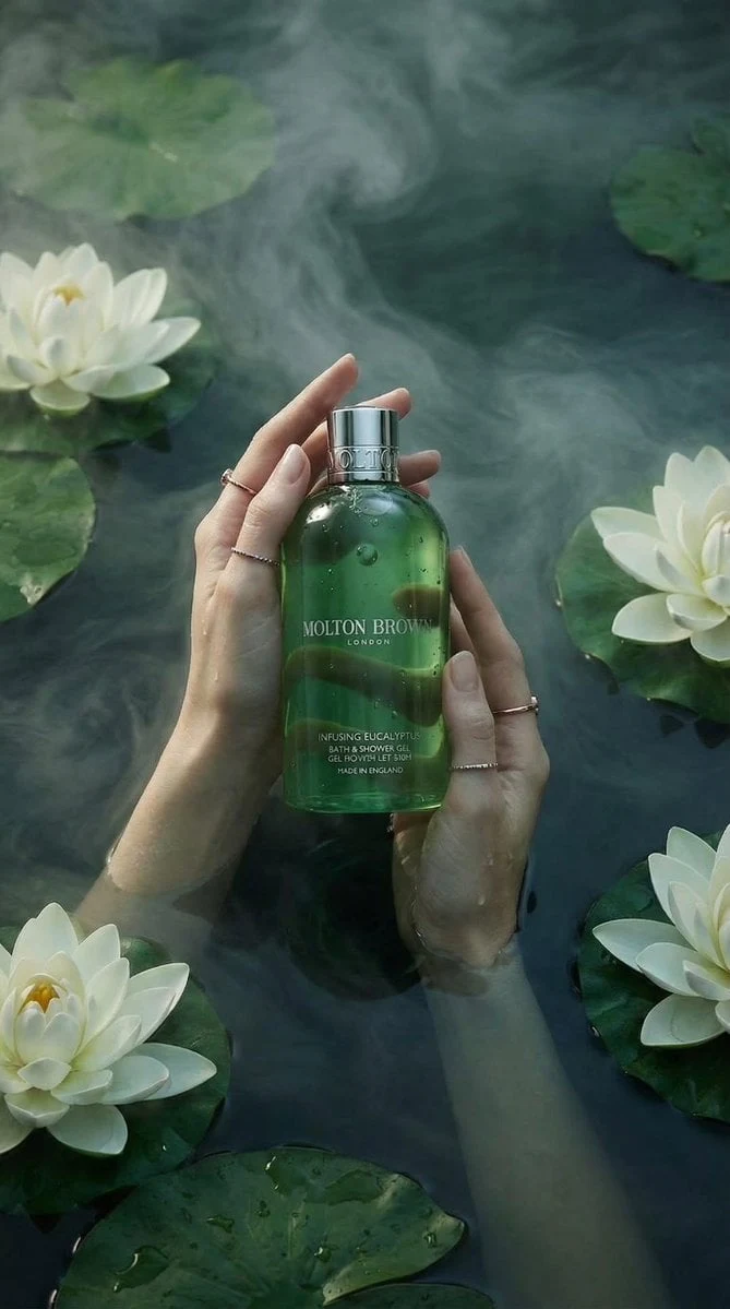 Fotografía de producto de lujo: un frasco de gel de baño y ducha verde translúcido sostenido delicadamente por dos manos femeninas...