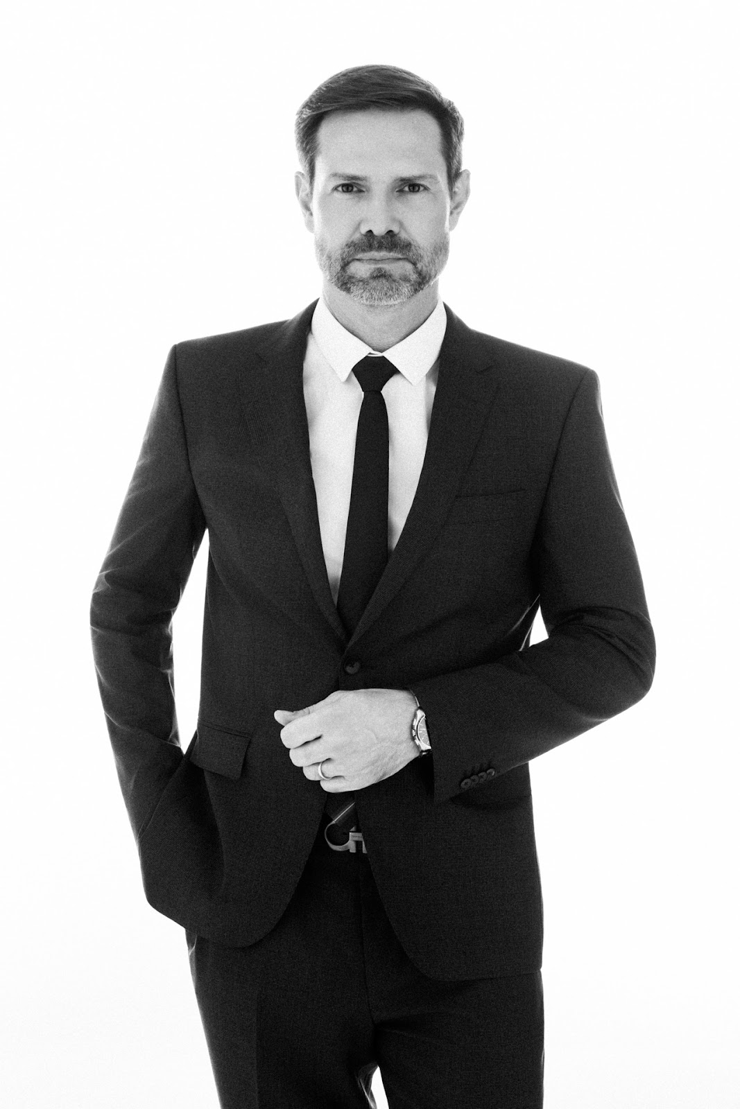 Retrato corporativo masculino em preto e branco com terno e gravata sobre fundo claro.