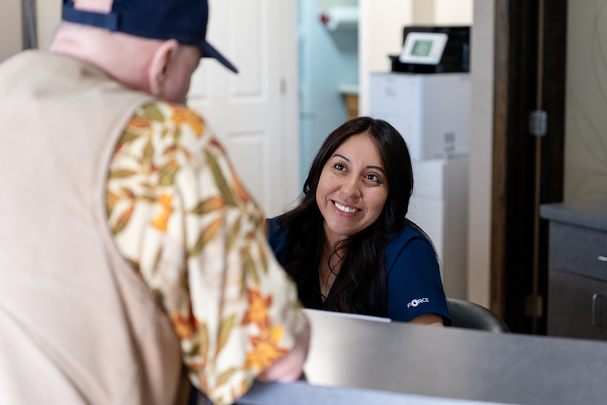 A smiling front desk team member helping a patient check in