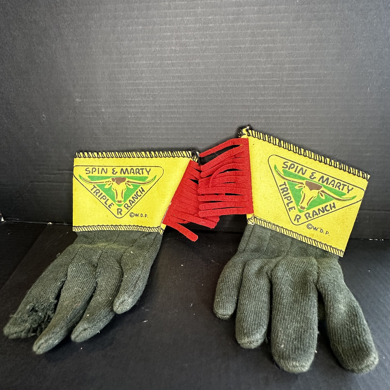 Pair of 1950s Disney Spin and Marty Triple R Ranch children's western play gloves with olive green knit fabric hands, flared yellow vinyl gauntlet cuffs with black whipstitching, red felt fringe, and screen-printed longhorn steer head logo