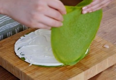 Trải từng miếng bánh crepe trà xanh ra mặt phẳng xếp chồng lên nhau, xen kẽ giữa các miếng bánh crepe là bánh cho kem sữa tươi, tráng đều.