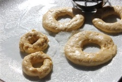 Dùng dụng cụ cắt, cắt hình donut, rồi để ra khoảng 10 phút trước khi chiên cho nở. Để lửa lớn cho nóng dầu rồi hạ lửa riu riu khi bỏ bánh vào chiên, nhớ đảo bánh để bánh nở đều 2 mặt và chờ bánh vàng thì vớt ra.