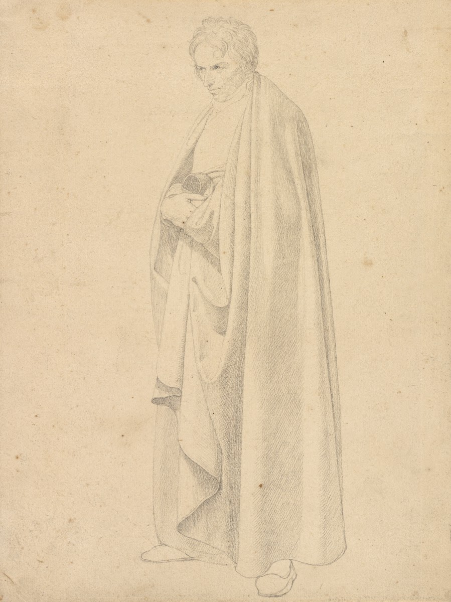 Joseph Wintergerst in a Floor length Coat Standing with his Hands Placed on Top