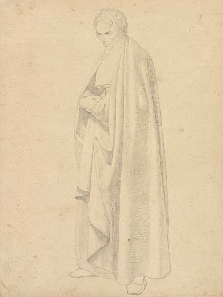 Joseph Wintergerst in a Floor length Coat Standing with his Hands Placed on Top