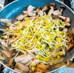 Đun nóng chảo với dầu ăn, cho hành tây và nấm vào xào hơi chín thì cho thị gà vào xào đến khi thịt gà không còn hồng nữa thì cho giá vào đảo đều. Làm sốt: cho nước mắm, nước cốt chanh, 3 muỗng tương ớt Thái vào chén và khuấy đều. Cho bún ra tô, xếp xà lách xung quanh, thêm thịt nấm đã xào vào giữa, rưới nước sốt lên, rắc chút đậu phộng rang và hành rồi trộn đều là có thể thưởng thức.