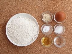 Trứng đập ra bát, dùng đũa đánh tan. Đổ bột ra khay rộng, thêm đường, nước, dầu, trứng và baking soda