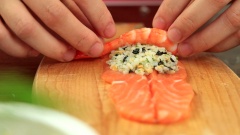 Tạo hình: Trải miếng cá hồi ra, phết 1 lớp cơm mỏng và chừa một phần đầu miếng cá để tạo hình đẹp mắt hơn, đặt 1 con tôm lên, chừa đuôi ra ngoài, cuộn tròn lại.