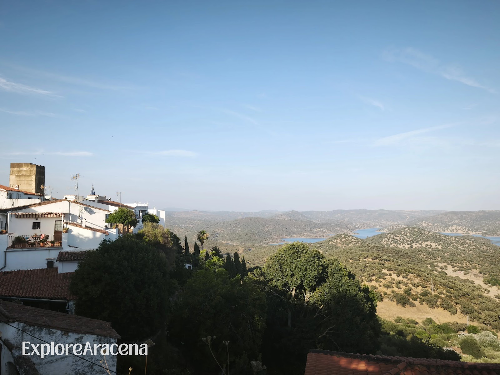 White houses on Zufre’s steep hillside above the reservoir, with Sierra hills stretching into the distance from the Paseo de los Alcaldes.