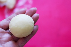 Sau đó chia nhỏ khối bột thành những viên nhỏ có cùng kích thước. Vê hơi tròn rồi ấn dẹp. Cho ít nhân đậu đỏ vào giữ, bọc kín nhân đậu lại rồi vê tròn.
