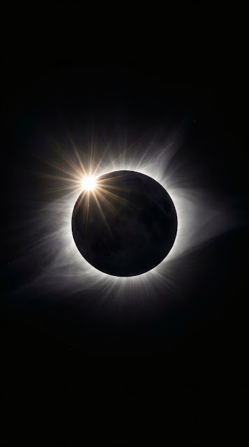 Total solar eclipse diamond ring effect with brilliant white solar corona flare against pitch-black cosmic space.