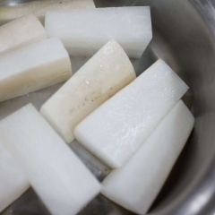 Đun nóng 1 muỗng canh dầu ăn trong nồi, cho củ cải cho chiên cháy xém các mặt. Sau đó đổ nước dùng (nấu từ cá cơm và rong biển) vào, thêm đường vàng, nước tương, nước màu, tỏi băm vào, đun sôi cho củ cải gần chín và ngấm đều sốt khoảng 10 phút. Cuối cùng thêm bạch tuộc và ít dầu mè vào, đun tiếp 5 phút.