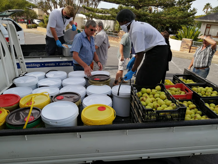 Soup, apples, and bread are loaded onto a bakkie by volunteers.