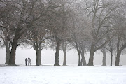 People walk between trees in freezing temperatures in Sefton Park, Liverpool, UK, on December 12 2022. 