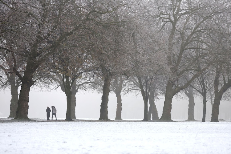 People walk between trees in freezing temperatures in Sefton Park, Liverpool, UK, on December 12 2022.