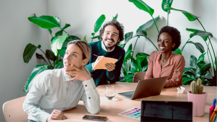 Three office workers collaborate at a desk