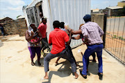 Residents carry goods which they took from a looted shop owned by foreign nationals on January 22, 2015 in Soweto. File photo.