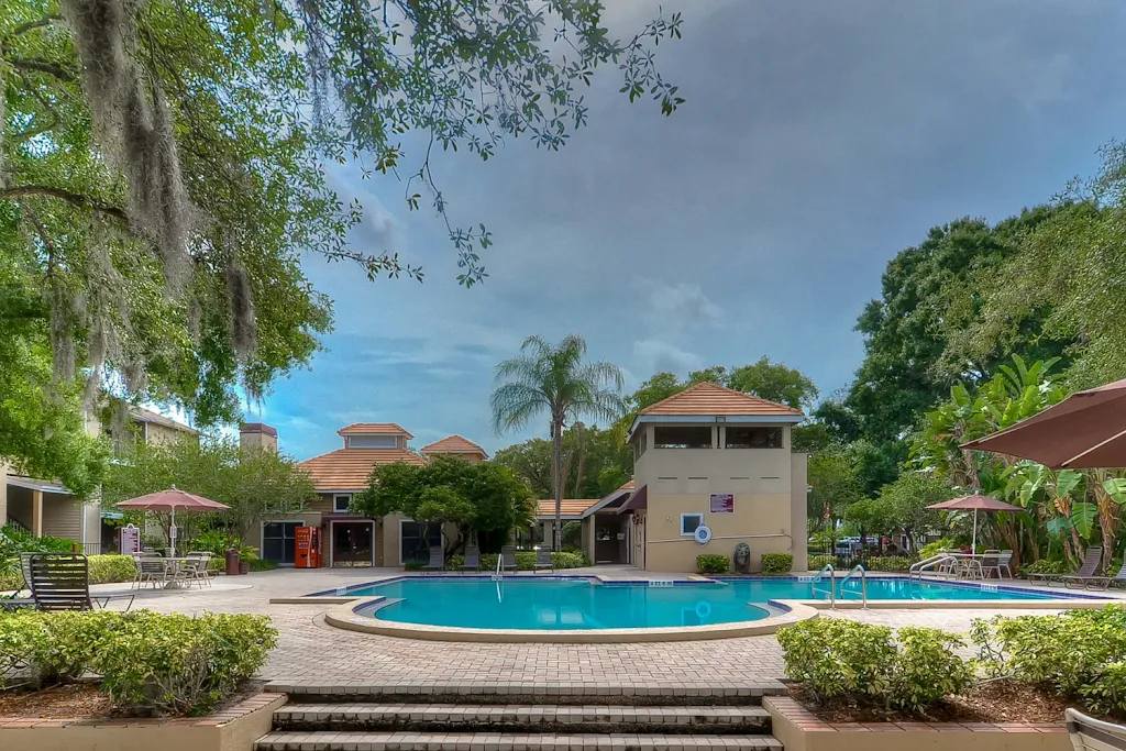 Community swimming pool with palm trees and clubhouse in the background.