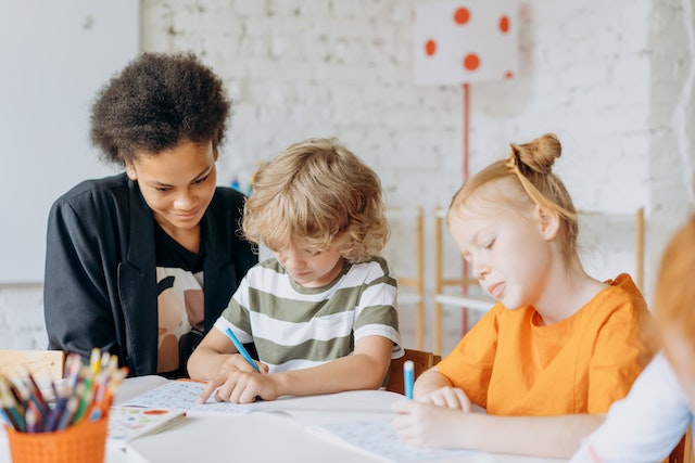 woman looking at children writing