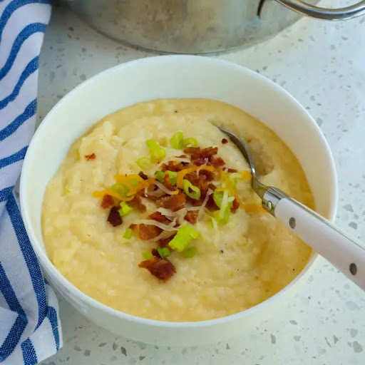 Smooth and Creamy Cheese Grits garnished with bacon and green onions are the perfect side dish for eggs,  andouille sausage, pork chops, barbecued ribs, and sauteed shrimp, 

