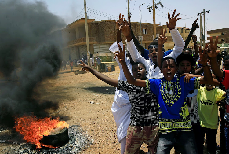 Sudanese protesters gesture and chant slogans at a barricade along a street, demanding that the country's Transitional Military Council hand over power to civilians, in Khartoum, Sudan, on June 5 2019.