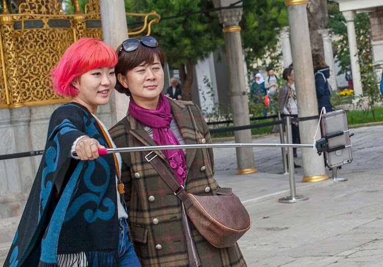 A mother and daughter use a selfie stick outside Hagia Sophia in Istanbul.