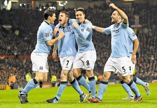 Livewire James Milner of Manchester City celebrates with his teammates after scoring the opening goal during the Premiership match between Manchester United and Manchester City at Old Trafford last night