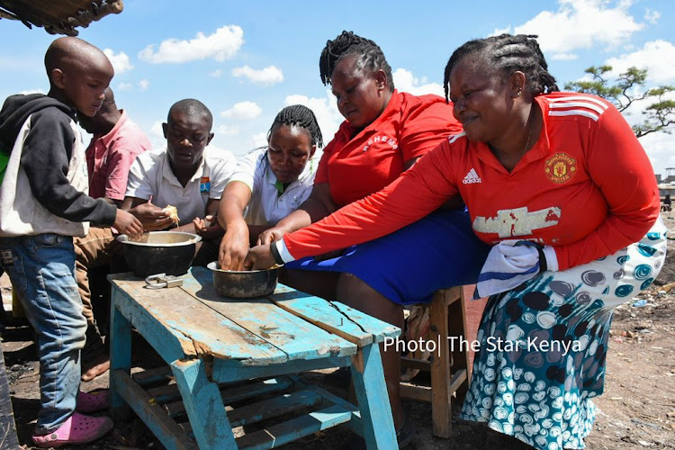 A family in Mukuru Kwa Njenga slums share a hearty meal outside their shelter in Mukuru Kwa Njenga slums after their house was demolished on 22, November 2021.- MERCY MUMO