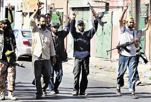 Libyan rebel fighters celebrate after taking partial control of the coastal town of Zawiyah, 50km west of Tripoli, yesterday. The rebels hoisted their flag in the centre of the town after the most dramatic advance in months cut off Tripoli from its main link to the outside world Picture: BOB STRONG/REUTERS