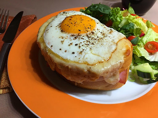 A gorgeous Croque-madame topped with a fried egg with salad on the side.