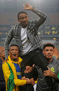 Mothobi Mvala and Ronwen Williams lift Sundowns coach Rulani Mokwena after the match.