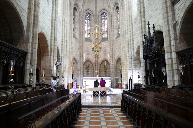 The Dean of St. George's Cathedral Michael Weeder and Archbishop of Cape Town Thabo Makgoba stand at the casket containing the body of Archbishop Desmond Tutu at St. Georges Cathedral, in Cape Town, on December 30, 2021.