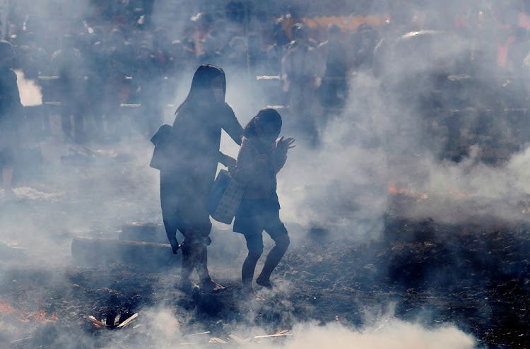 A woman and a girl wearing protective mask, amid the coronavirus disease (COVID-19) outbreak, walk across smouldering hot ground at the fire-walking festival, called hiwatari matsuri in Japanese, at Mt.Takao in Tokyo, Japan, March 14 2021.