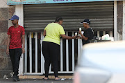 Residents buy ice creams through a partially closed shop door, 20 March 2023.