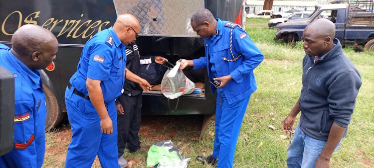 Officers at Kabete police station inspect the bus transporting illicit brew