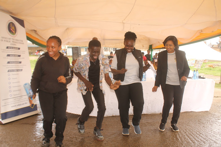 Head of Mavoko Law Courts chief magistrate Barbara Ojoo (3L) with Office of the Registrar Magistrate's Court representative Shilla Mwaniki (R) join youths in a jig during the Mavoko Law Courts Open Day in Mlolongo, Machakos County on April 26, 2024.