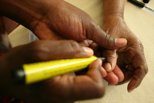 An election official marks a voter's thumb.