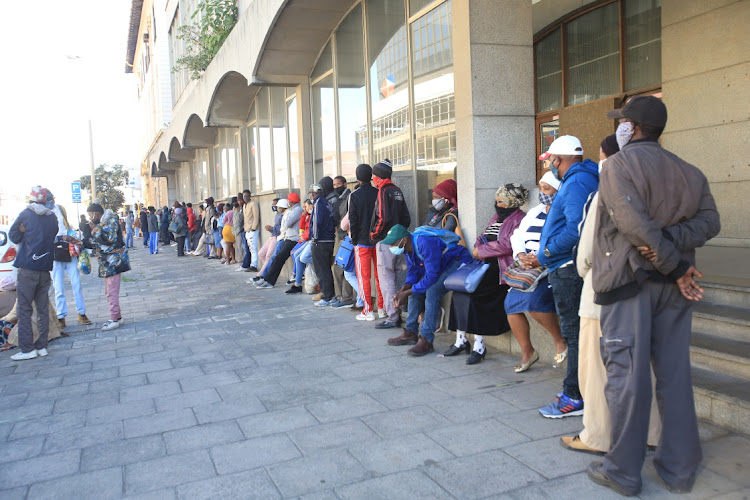 People queue for their social relief of distress grant payments in East London. File image.