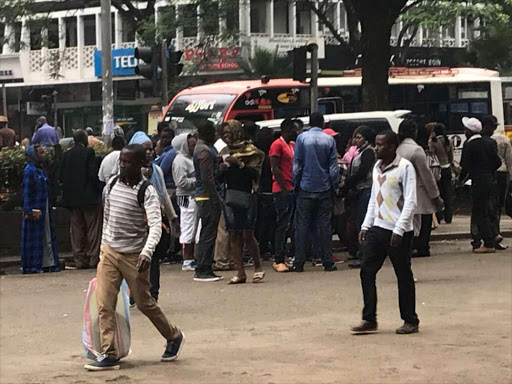 Crowd gathers around a group selling coupons and offer tickets on Moi Avenue